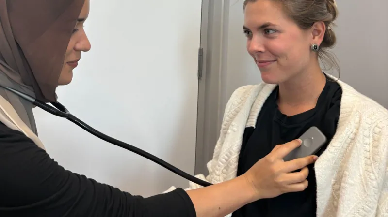 Médica de hijab ausculta paciente usando estetoscópio digital conectado a um smartphone