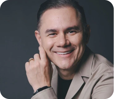 Retrato de homem sorridente de blazer bege, mão no rosto