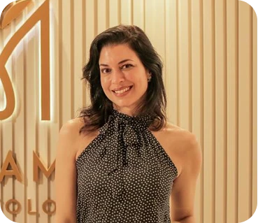 Retrato de mulher sorridente de vestido estampado em ambiente com painel de madeira dourada