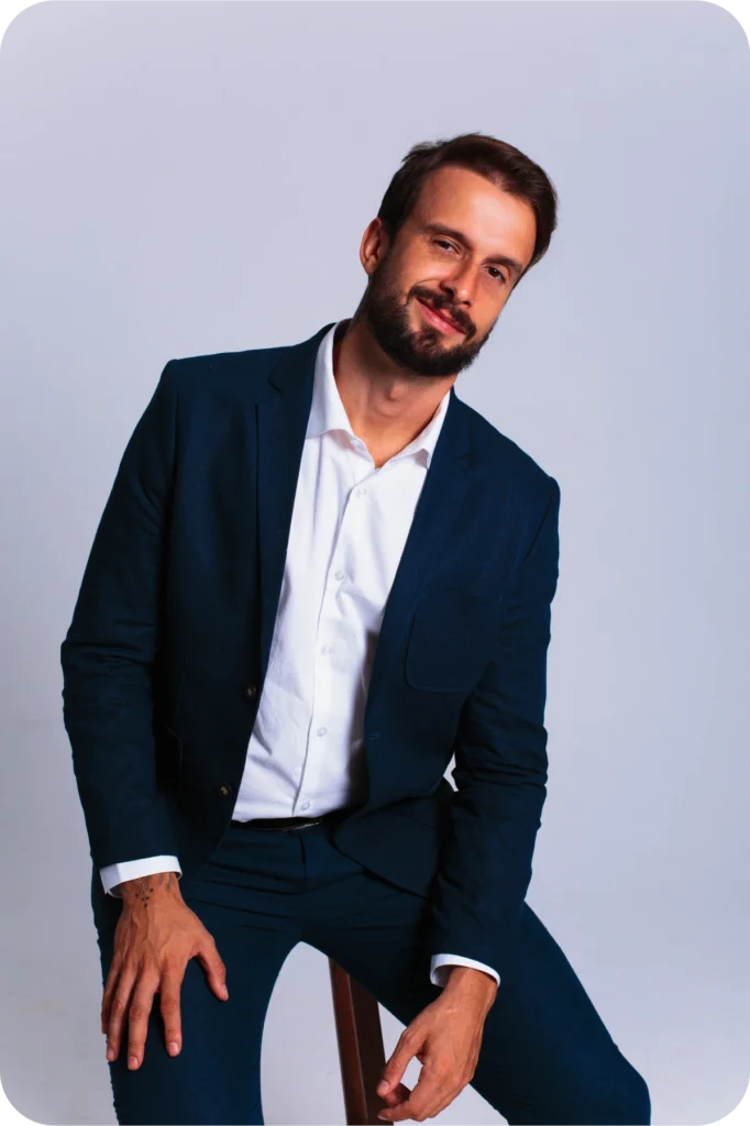 Retrato de Douglas Gomides de terno azul-marinho, apoiado em um banco