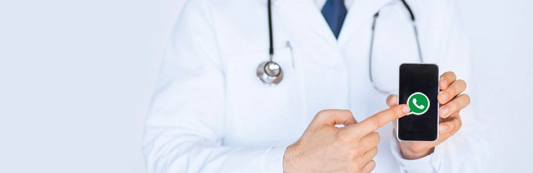 Médico de jaleco branco segura celular exibindo o ícone do WhatsApp