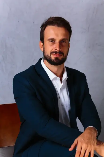 Retrato de Douglas Gomides de terno azul-marinho e camisa branca, sentado
