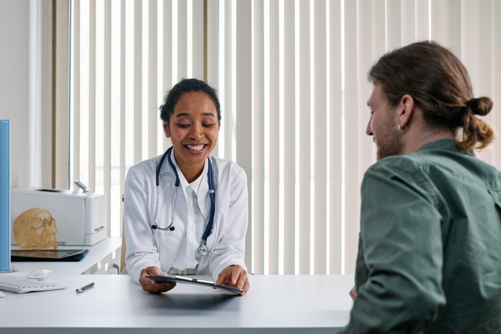 Médica sorridente mostra tablet a paciente em consultório com crânio anatômico sobre a mesa