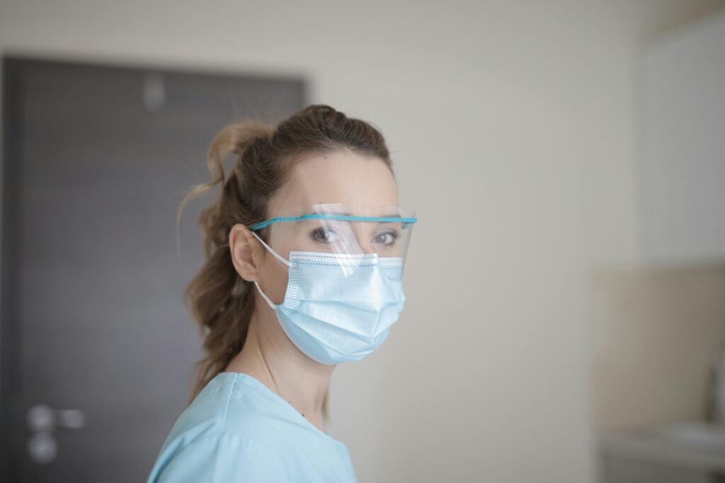 Profissional de saúde de máscara e protetor facial, scrubs azul-claro