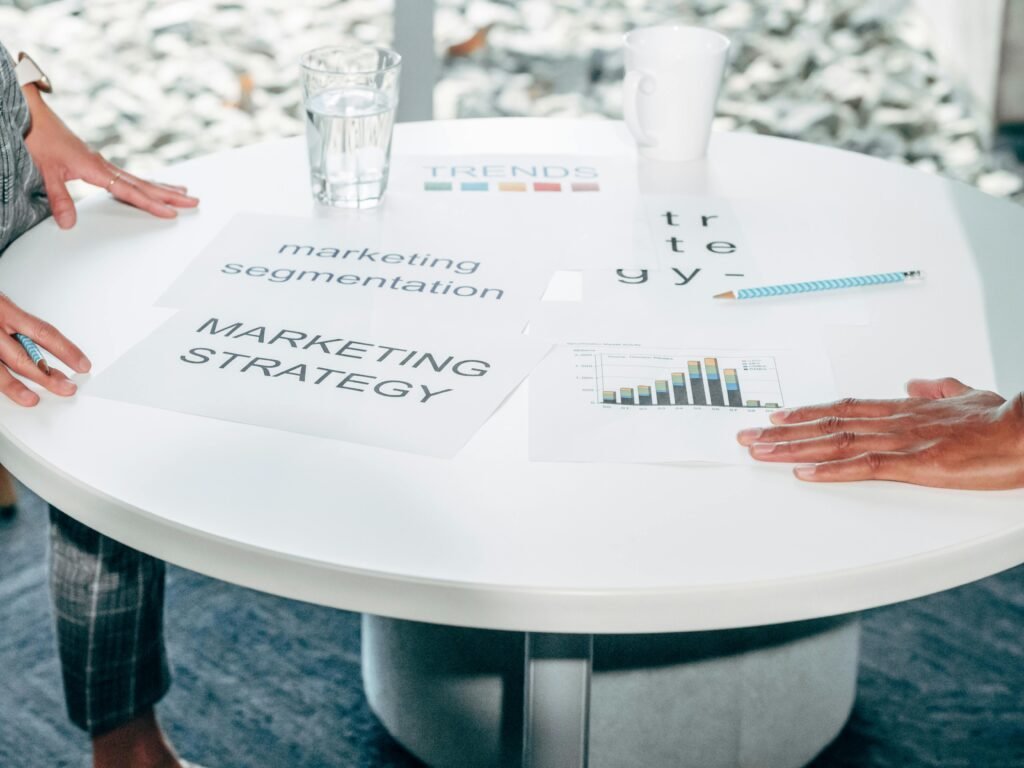 Folhas impressas com os dizeres 'marketing strategy' e 'trends' sobre mesa redonda