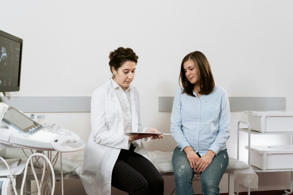 Médica mostra resultado em tablet a paciente sentada em maca, com aparelho de ultrassom ao lado