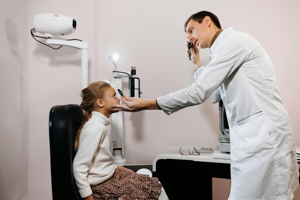 Médico examina os olhos de uma menina com oftalmoscópio em consultório