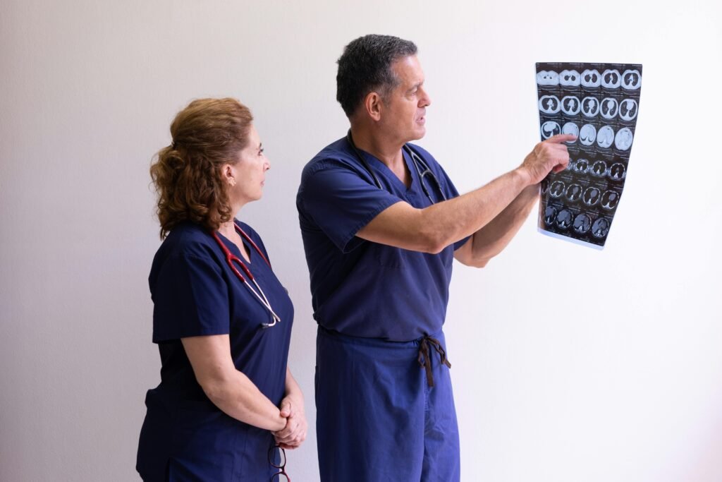 Médico aponta para exames de tomografia enquanto colega observa
