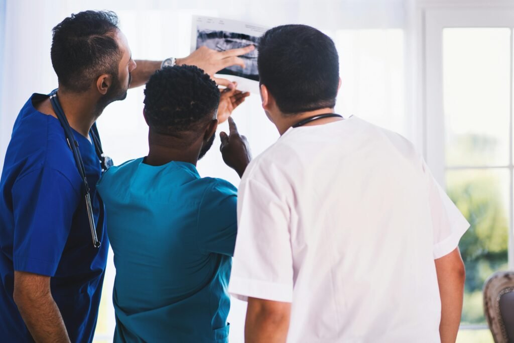Três profissionais de saúde de costas analisam uma radiografia em conjunto