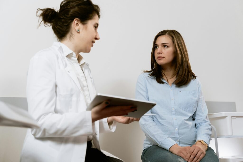 Médica de jaleco branco conversa com paciente segurando um tablet