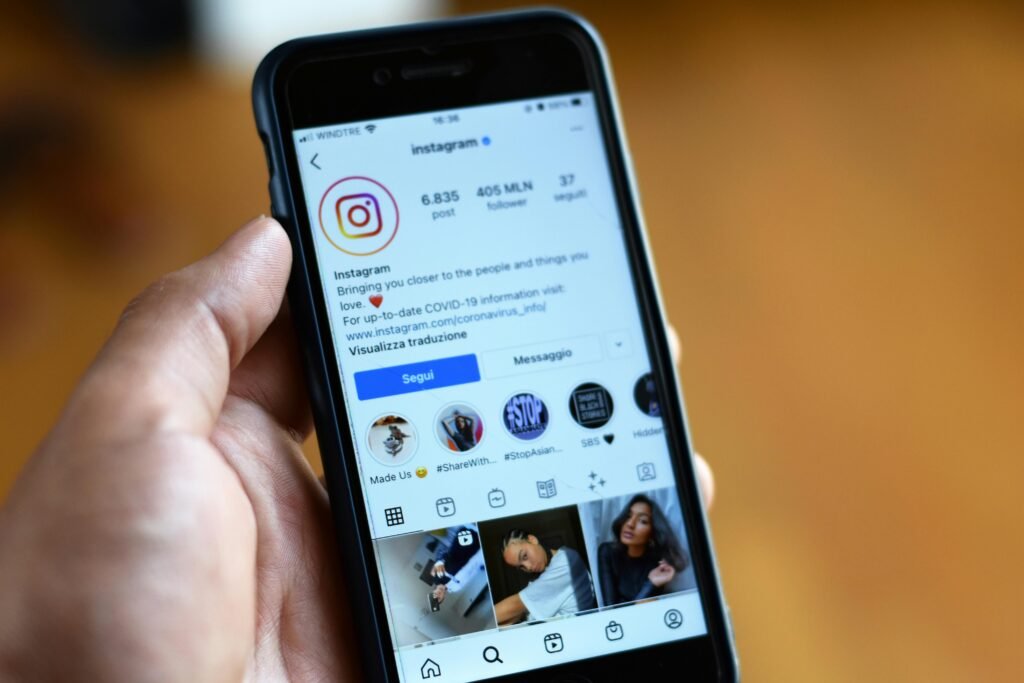 Mão segura celular exibindo o perfil do Instagram no aplicativo