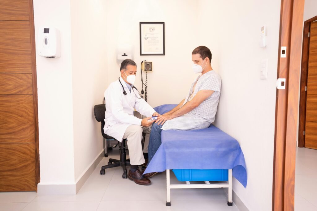 Médico de máscara mede a oxigenação de um paciente sentado em maca de consultório
