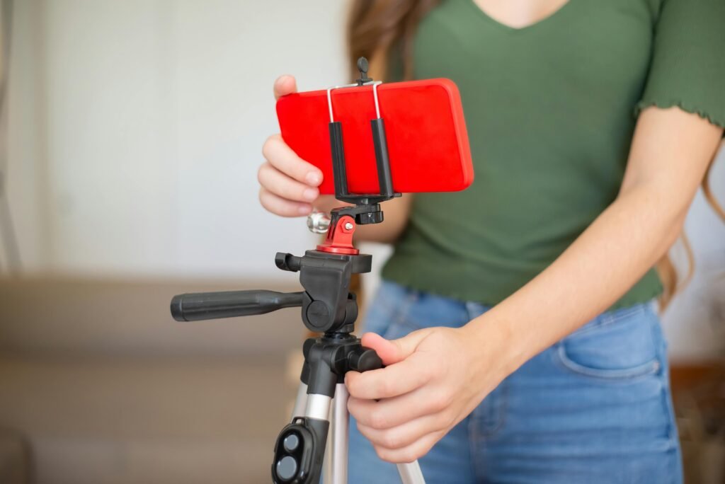 Pessoa monta celular vermelho em tripé com controle remoto para gravar vídeo