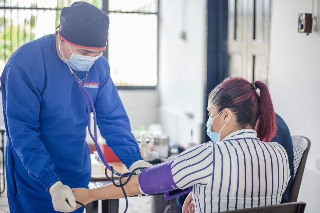 Voluntário de banco de sangue mede a pressão de uma doadora antes da coleta