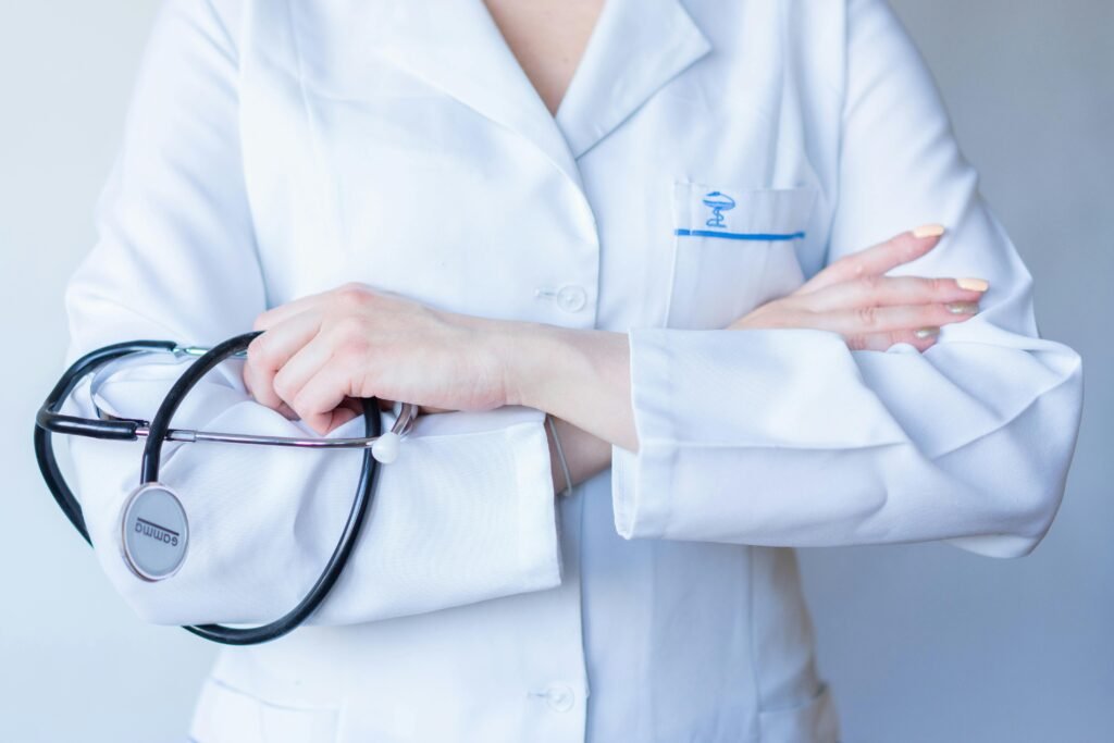 Médica de jaleco branco com estetoscópio, braços cruzados