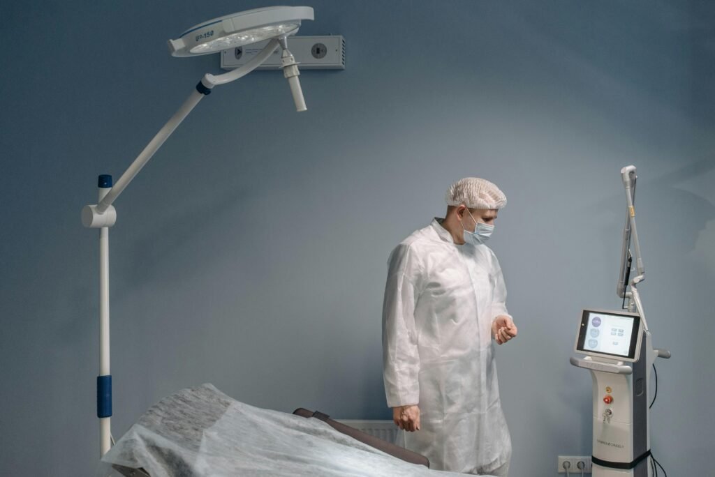 Profissional de saúde paramentado ao lado de aparelho a laser em sala de procedimento estético