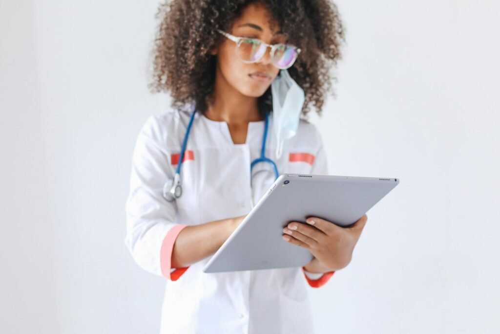 Médica de óculos e estetoscópio analisa dados em um tablet