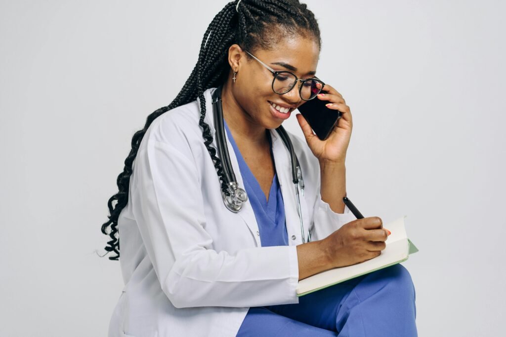 Médica sorridente fala ao telefone enquanto anota em um caderno