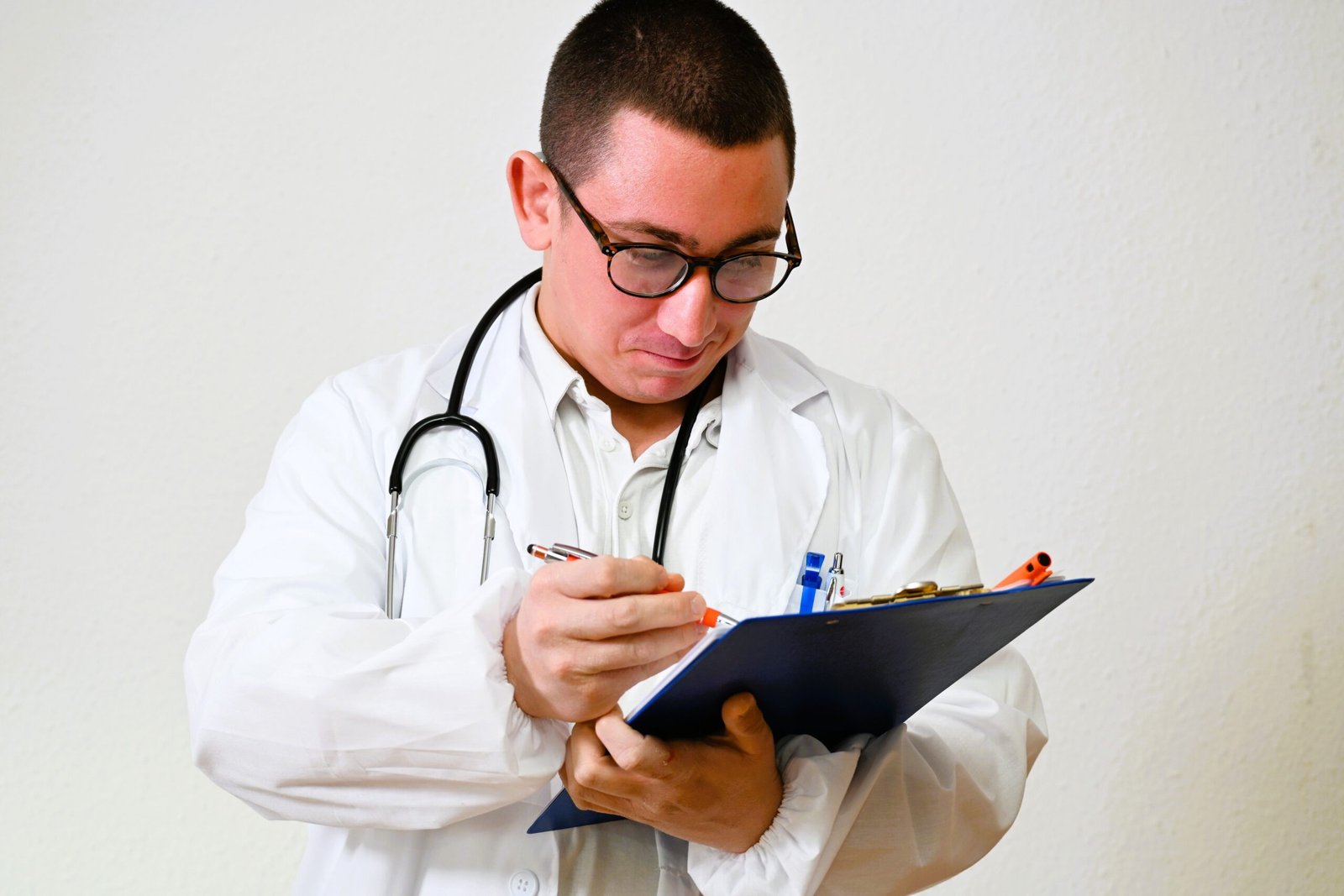 Médico de óculos e estetoscópio faz anotações em prancheta