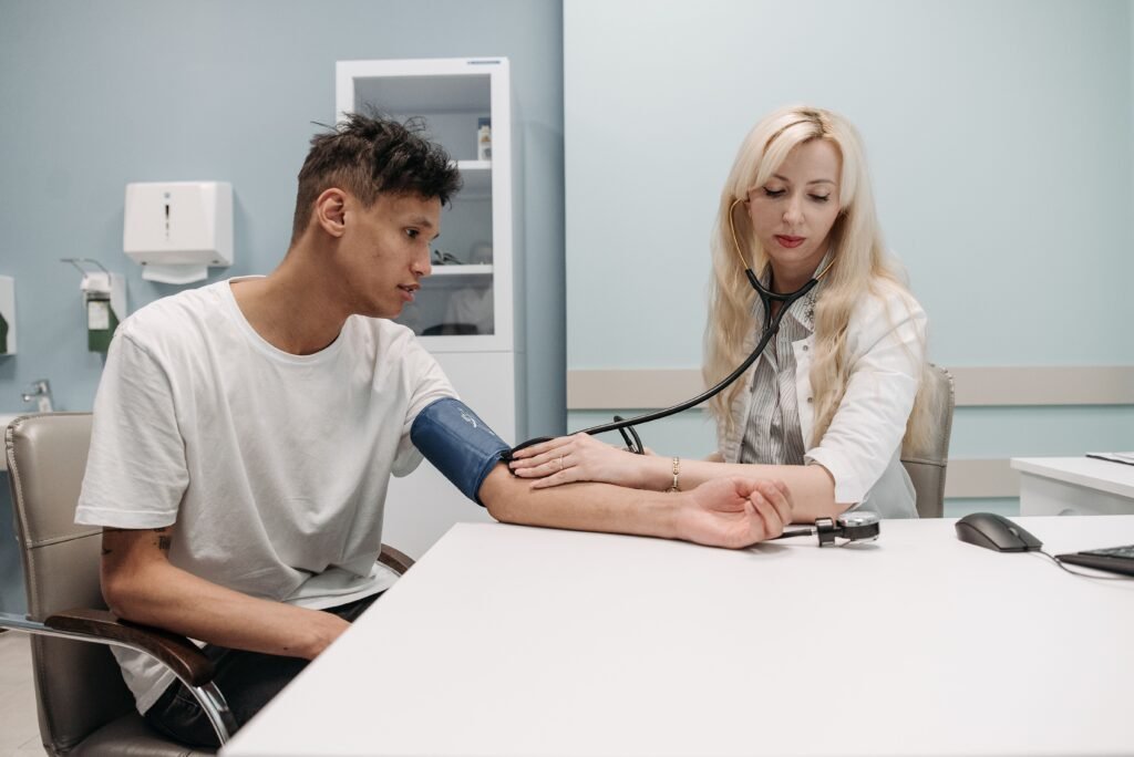 Médica mede a pressão arterial de um paciente jovem em consultório